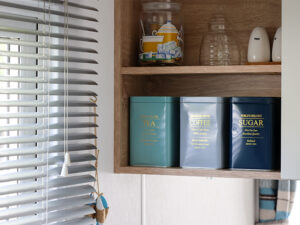 Teekisten en keukenaccessoires in een gezellige stacaravan aan zee, perfect voor een ontspannen verblijf.