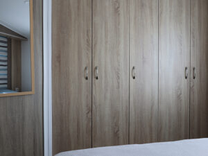 Ruime houten kast in luxe stacaravan aan zee, perfect voor opbergen tijdens je vakantie.