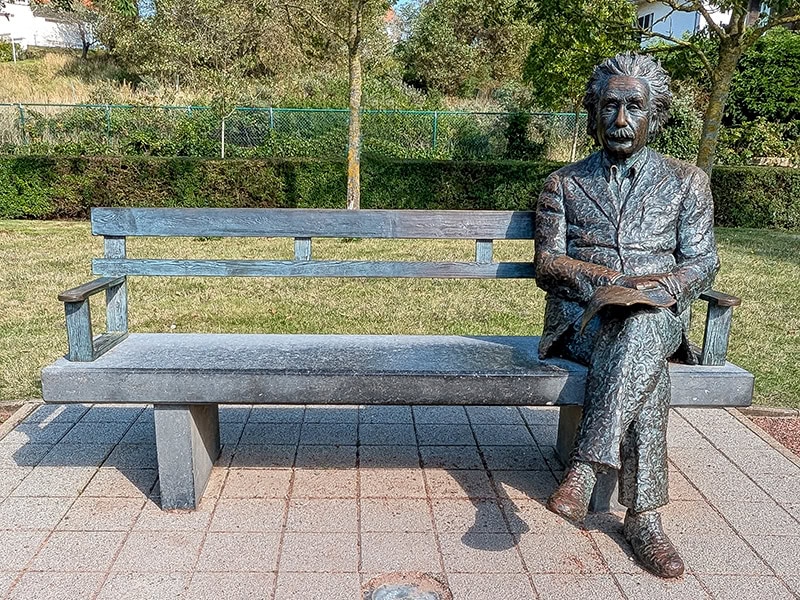 Steincorpus met zittende Albert Einstein beeld op bank in park, geschikte locatie voor jubilea, inspiratie, geschenken en jubileumdecoratie.