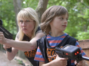 Vrouw en kind met laserpistolen in bos. Veilig laser tag spel voor gezinnen in de natuur.